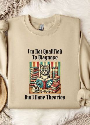 a beige sweatshirt with a printed design of a cat surrounded by books and a cup of coffee, along with the text "I'm Not Qualified To Diagnose But I Have Theories".