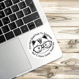 A sticker with a cat wearing glasses and the text "I'm Not Qualified To Diagnose, But I Have Some Theories" is placed on a laptop keyboard.