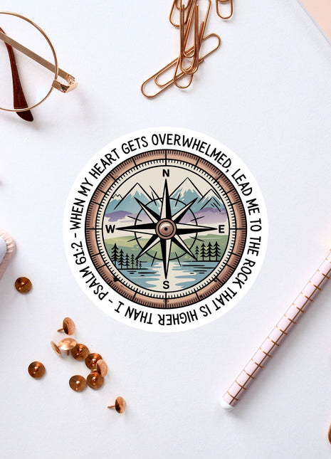 a compass with a mountain landscape, surrounded by various office supplies such as a pen, a notebook, and a pair of glasses.