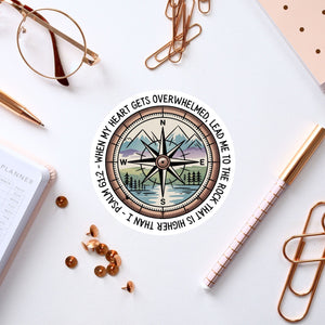 a compass with a mountain landscape, surrounded by various office supplies such as a pen, a notebook, and a pair of glasses.