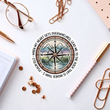 a compass with a mountain landscape, surrounded by various office supplies such as a pen, a notebook, and a pair of glasses.