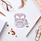 a sticker of a pair of earbuds with the text "Fantasy Audiogirl" on it, surrounded by various office supplies such as pens, a notebook, and a pair of glasses.