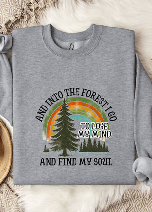 A gray sweatshirt with a graphic design of a forest and a rainbow, along with the text "AND INTO THE FOREST I GO TO LOSE MY MIND AND FIND MY SOUL".