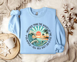 a light blue sweater with a picture of a sunset and palm trees on it