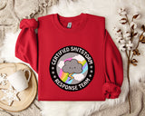 a red sweater with a graphic design on it, placed on a white fur rug. The design includes a cloud with a lightning bolt and the text "Certified Shitstorm Response Team".