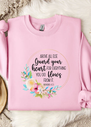 A pink sweatshirt with a floral design and text printed on it, placed on a white fur rug.