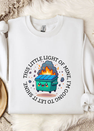 a white t-shirt with a graphic design depicting a fire-breathing trash can, surrounded by a circular design with the text "This little light of mine is coming to an end".