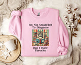 A pink sweatshirt with a cat illustration and text, placed on a white fur rug with a mug and a branch of cotton flowers nearby.