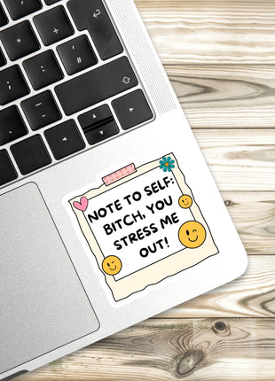 A sticker with a humorous message is placed on a laptop keyboard.