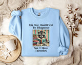 A light blue sweatshirt with a graphic design of a raccoon wearing glasses and surrounded by books, along with text that reads "I'm Not Qualified To Diagnose But I Have Theories".