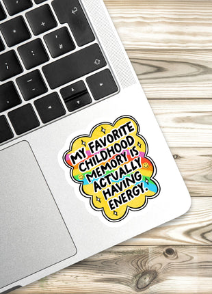 A sticker with a colorful design and text is placed on the edge of a laptop keyboard.