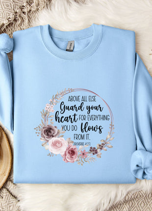 A light blue sweatshirt with a floral design and text printed on it, placed on a white fur rug.