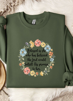 A green sweatshirt with a floral design and text printed on it, along with a mug and some white flowers on a white surface.