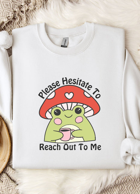 a white sweatshirt with a mushroom-like design and text, along with a mug and some flowers on a bed.