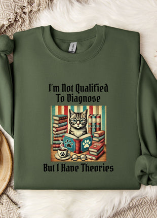 a green sweatshirt with a printed design of a cat surrounded by books and a cup of coffee, along with the text "I'm Not Qualified To Diagnose But I Have Theories".
