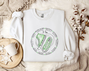 a white sweatshirt with a green sneaker on it