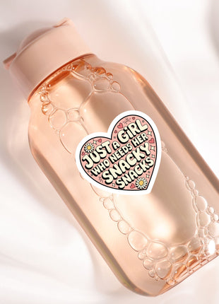 A pink bottle with a heart-shaped sticker that says "Just a girl who needs her snacks"