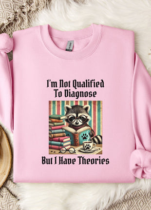 A pink sweatshirt with a graphic design of a raccoon reading books and the text "I'm not qualified to diagnose, but I have theories" printed on it, along with a mug and a plant.