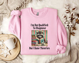 A pink sweatshirt with a graphic design of a raccoon reading books and the text "I'm not qualified to diagnose, but I have theories" printed on it, along with a mug and a plant.