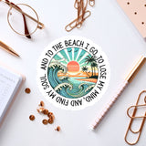 a sticker with a beach scene, surrounded by various office supplies such as pens, a notebook, and a pair of glasses.