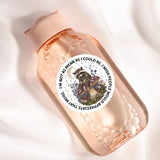 A pink bottle with a sticker featuring a raccoon sitting on a mushroom and surrounded by flowers and mushrooms.
