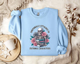A light blue sweatshirt with a graphic design of a skull surrounded by flowers and books, along with the text "Emotionally Attached to Fictional Characters".