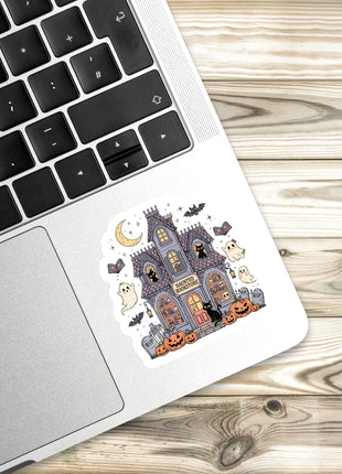 a sticker of a Halloween-themed house on a laptop keyboard.