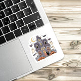 a sticker of a Halloween-themed house on a laptop keyboard.