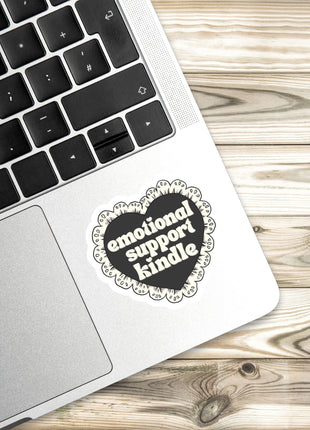A laptop with a heart-shaped sticker on the palm rest, placed on a wooden surface.