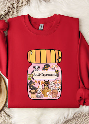 A red sweater with a graphic of a jar filled with cartoon dogs and the text "Ani-Dependsents" printed on it, along with a mug and some white flowers on a white fur rug.