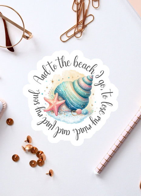 a sticker with a seashell and starfish design, surrounded by various office supplies such as pens, paper clips, and a pair of glasses.