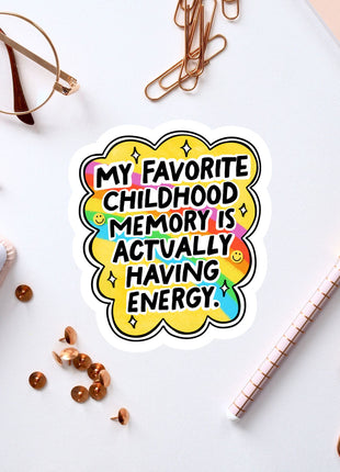 a sticker with a colorful design and text, surrounded by various office supplies such as a pen, a pair of glasses, and a notebook.
