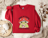 A red sweater with a mushroom graphic and the text "HANG IN THERE IT GETS WORSE" printed on it, along with a mug and a branch of cotton bolls.
