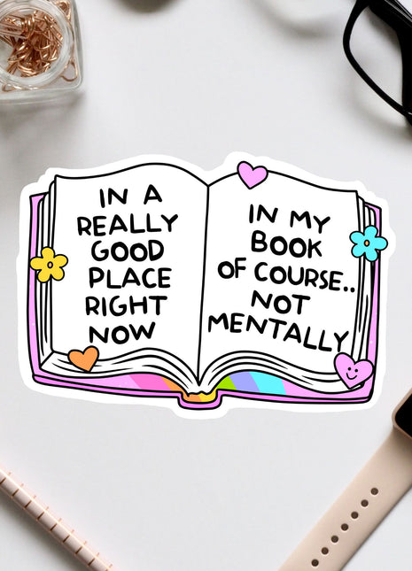 an open book sticker on a desk next to a pair of glasses