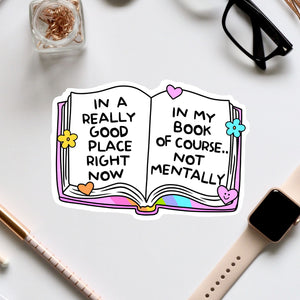 an open book sticker on a desk next to a pair of glasses