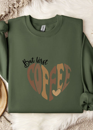 a green sweatshirt with a heart-shaped design and the text "But first coffee" printed on it, along with a mug and some flowers.