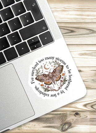 A sticker with a butterfly and floral design is placed on the edge of a laptop keyboard.
