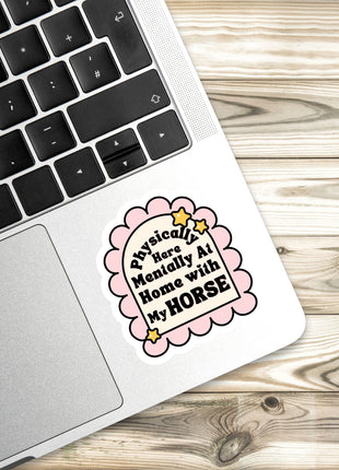 A sticker with a humorous text on a laptop keyboard, placed on a wooden surface.