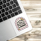 A sticker with a humorous text on a laptop keyboard, placed on a wooden surface.