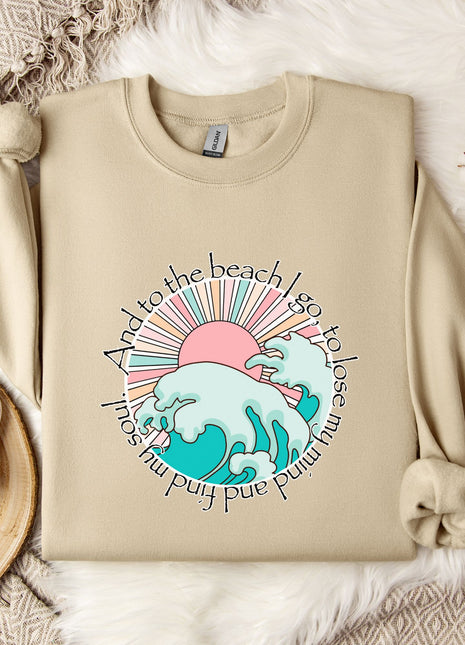 A beige sweatshirt with a graphic design depicting a beach scene, along with a mug, a branch of cotton bolls, and a snowflake.
