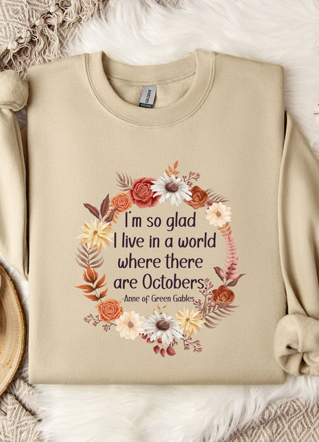A beige sweatshirt with a floral wreath design and a quote printed on it, along with a mug, a branch of cotton bolls, and a snowflake ornament.
