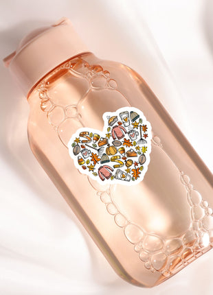 A pink bottle with a heart-shaped sticker featuring various fall-themed illustrations, such as pumpkins, leaves, and other seasonal objects.