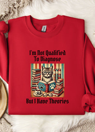 A red sweater with a cat graphic and text printed on it, along with a mug and a plant, all placed on a white surface.