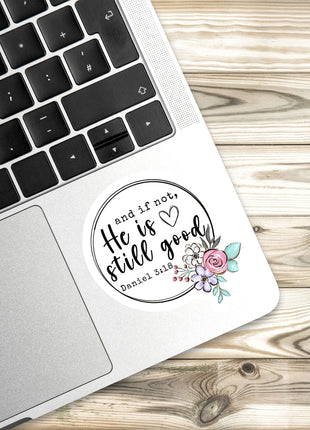 A sticker with a floral design and text is placed on the edge of a laptop keyboard.