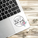 A sticker with a floral design and text is placed on the edge of a laptop keyboard.