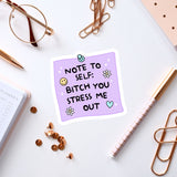 a purple sticker with a humorous message, surrounded by various office supplies and accessories such as a pen, a pair of glasses, and a notebook.