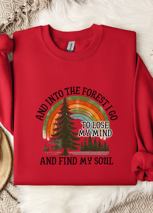 A red sweater with a graphic design of a forest and a rainbow, along with the text "AND INTO THE FOREST I GO TO LOSE MY MIND AND FIND MY SOUL".