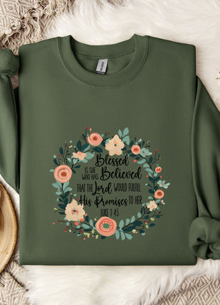 A green sweatshirt with a floral wreath design and text printed on it, placed on a white fur rug.