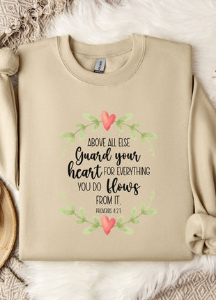 a beige sweatshirt with a printed Bible verse and a floral design, along with a mug, a white mug with a heart design, and some white flowers on a white fur-covered surface.