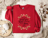 A red sweater with a printed message about guarding one's heart, along with a white mug and a branch of cotton bolls, all placed on a white fur rug.